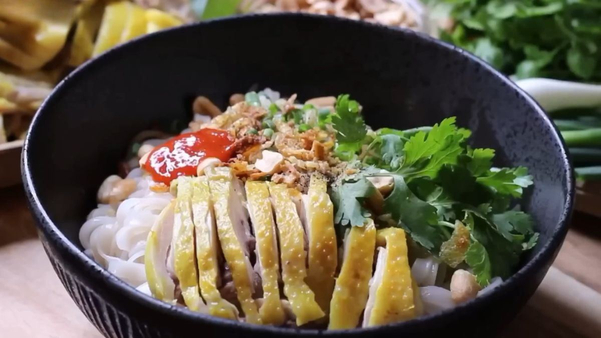 Sợi phở thấm đẫm sốt nâu óng, kết hợp với vị bùi của lạc rang và hành phi giòn tan tạo nên hương vị bùng nổ.